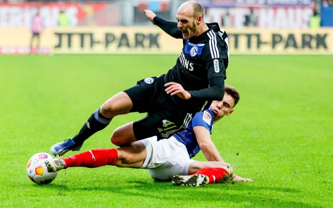 Der Kieler Nicolai Remberg (r) grätscht gegen den Schalker Henning Matriciani.