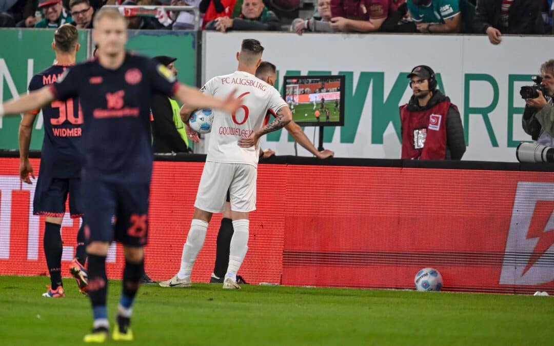 Schiedsrichter Sören Storks schaut sich die Foulszene noch einmal an und nimmt den Elfmeter für Augsburg dann zurück.