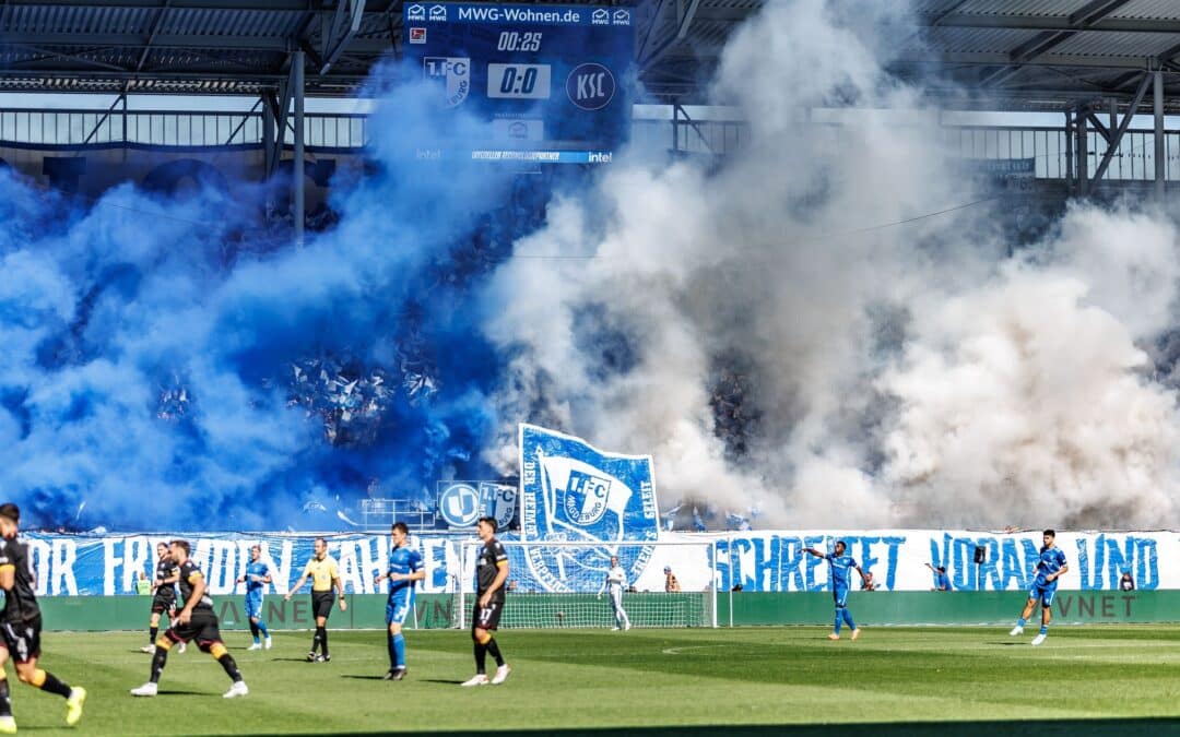 Die Magdeburger Fans zeigen ein fragwürdiges Banner und betonen dies mit Pyrotechnik.