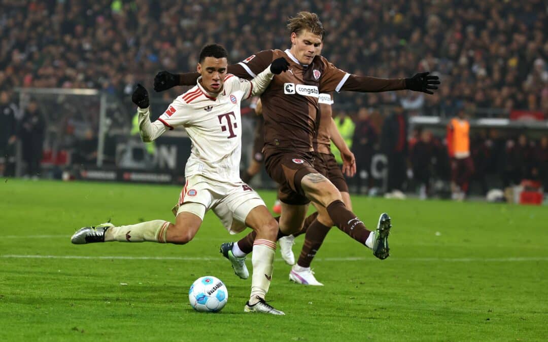 FC St. Paulis Abwehrspieler Eric Smith (r) verletzt sich beim Spiel gegen den FC Bayern.