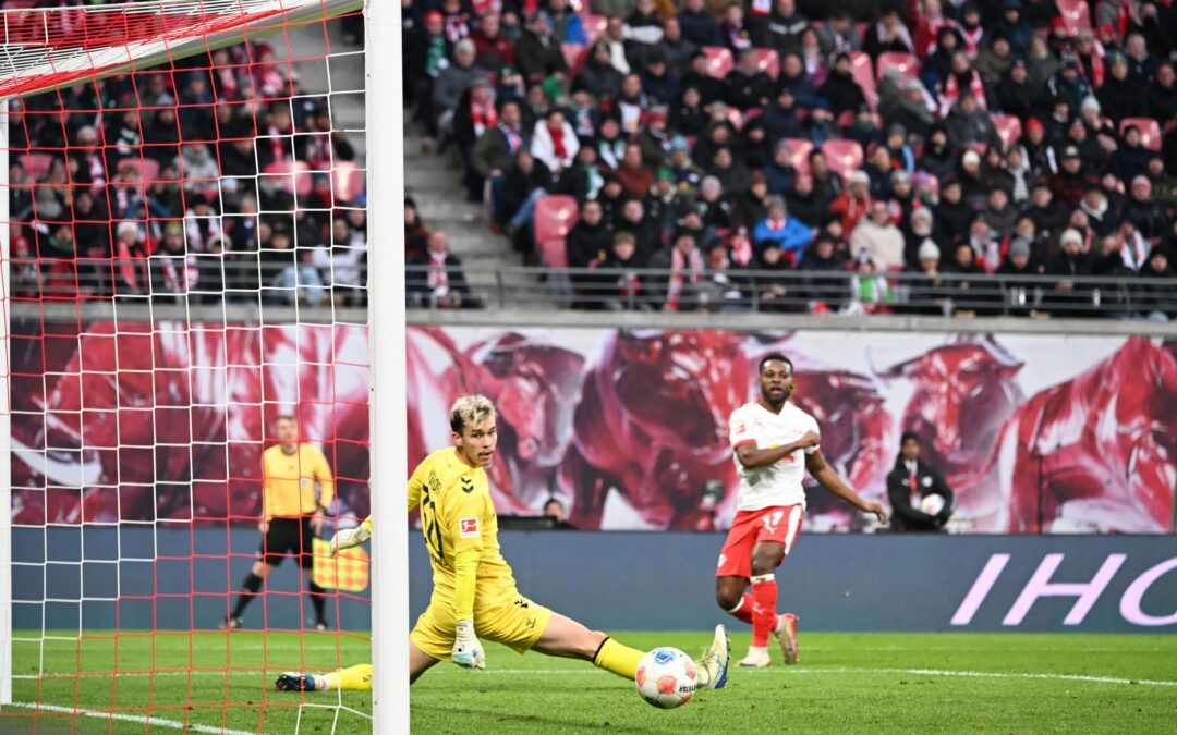 Bremens Torwart Mio Backhaus (l, Werder Bremen) und Ridle Baku (RB Leipzig) schauen dem Ball hinterher. Backhaus verhinderte mit seinen Paraden einen frühen Rückstand der Gäste in Leipzig.
