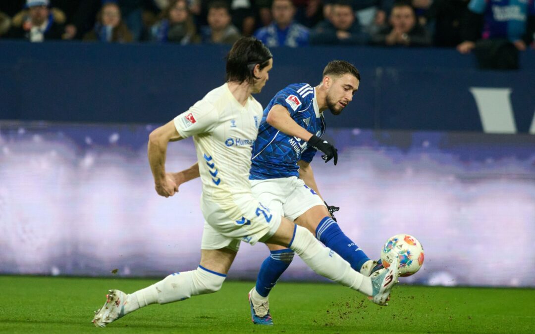 Das 1:0 für Schalke: Adil Aouchiche schießt, Magdeburgs Jean Hugonet fälscht mit der Fußspitze ab - und der Ball fliegt im hohen Bogen ins Tor.