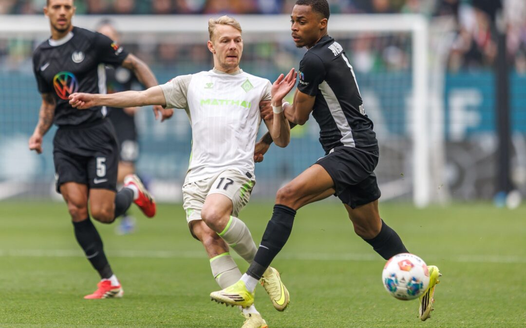 Werders Marco Grüll (l) wird von Wolfsburgs Jeanuel Belocian bedrängt.